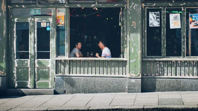 Zwei Menschen unterhalten sich hinter dem Fenster eines Cafés – erstes BDSM-Treffen